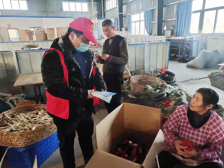 圖為網格員在標準化廠房內宣傳應急知識宣傳手冊.jpg