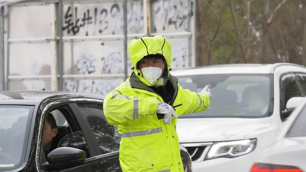 圖為正在車流中頂風冒雪指揮交通的交警.jpg