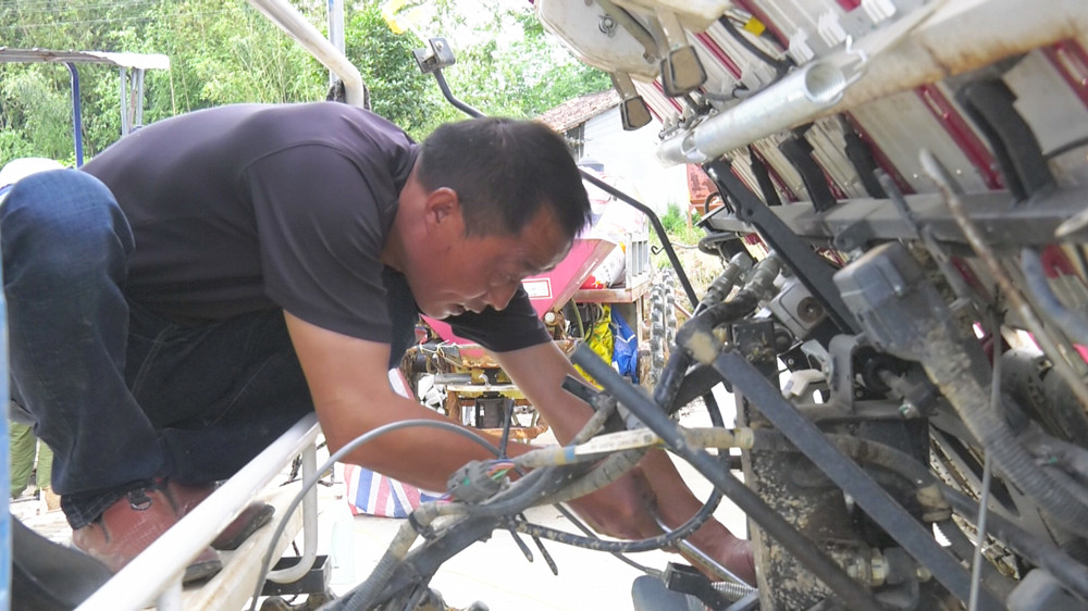 圖為徐向陽正在為農(nóng)機戶維護(hù)農(nóng)機.jpg