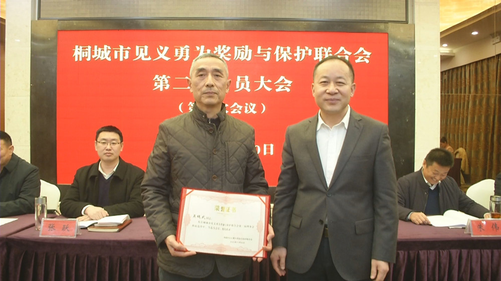 圖為市委常委、政法委書(shū)記為新當(dāng)選的桐城市第二屆見(jiàn)義勇為余保護(hù)聯(lián)合會(huì)會(huì)長(zhǎng)吳繩武頒發(fā)任命證書(shū).jpg