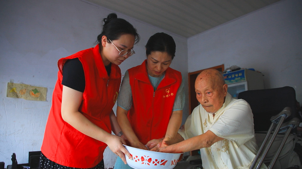 圖為社區(qū)志愿者正在部分行動(dòng)不便的退伍軍人家長(zhǎng)開(kāi)展關(guān)愛(ài)服務(wù).jpg