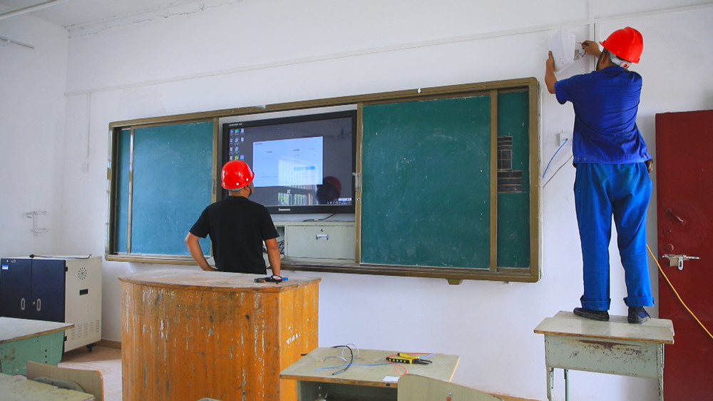 圖為高橋中心小學內技術人員正在調試新安裝的班班通教學一體機.jpg