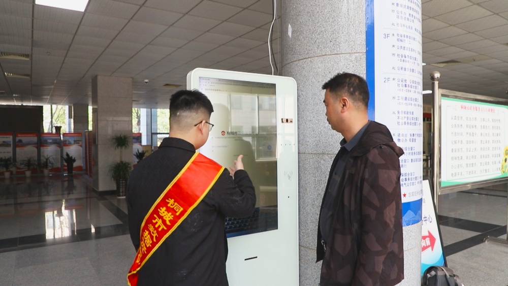 圖為市民汪先生正在工作人員的引導下使用政務服務智能導辦助手辦理業務.jpg